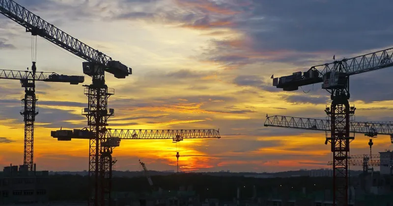 Zonsondergang met enkele hijskranen op de achtergrond